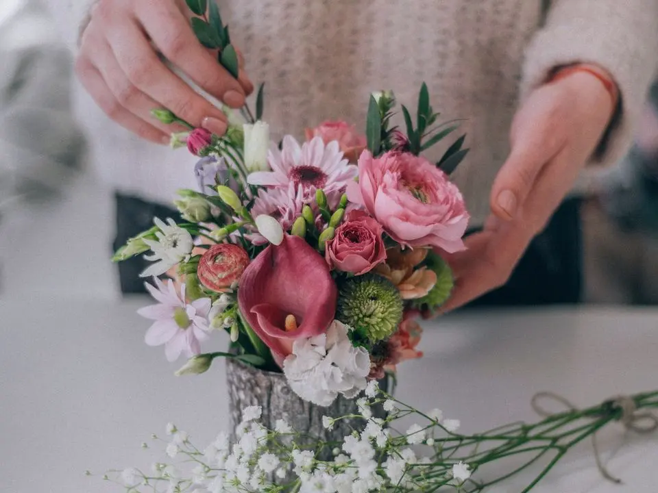 Le mani di una fiorista con un mazzo di fiori rosa e bianchi